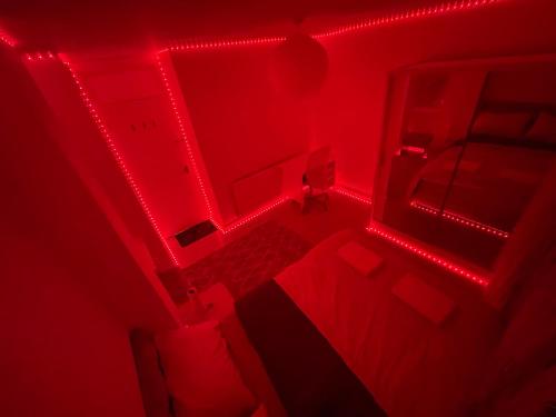 een kamer met rode verlichting, een bed en een bureau bij Flat A in Londen