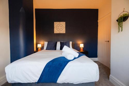 a bedroom with a large white bed with blue accents at Redcar House By Horizon Stays in Redcar