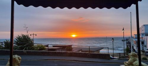 a sunset over the ocean with a table on a balcony at Royal Pier in Sandown