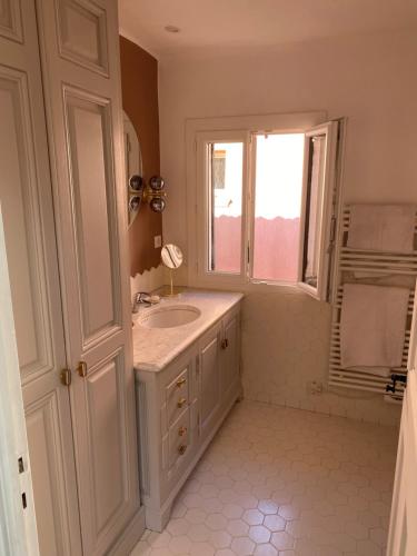 a white bathroom with a sink and a window at Studio centre ville Saint Tropez avec parking in Saint-Tropez