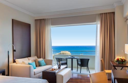 a hotel room with a couch and a dining room at Elysium Resort & Spa in Faliraki