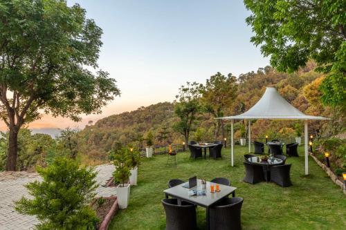 a patio with tables and chairs and a white umbrella at Alaya Stays Live Life 2BHK Apartment in Kasauli in Kasauli