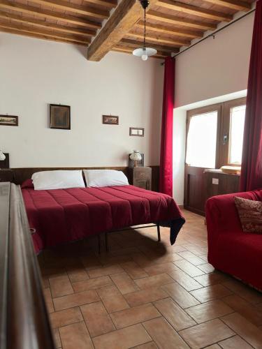 a bedroom with a bed with red sheets and a couch at La Casetta in San Giovanni delle Contee