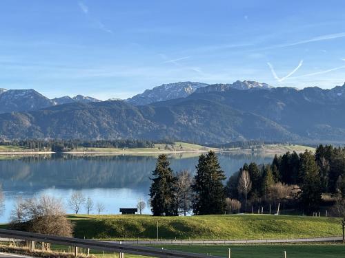 vistas a un lago con montañas en el fondo en Allgäu Pension Ab in den Süden en Bernbeuren