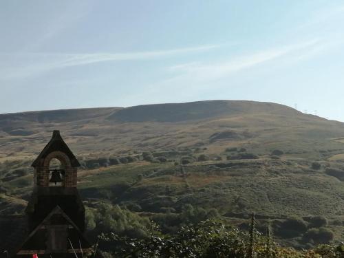 a church steeple with a mountain in the background at Walkers rest (Afan Valley) sleeps 5 in Cymmer