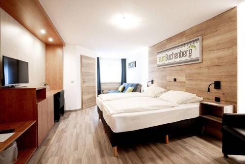 a bedroom with two beds and a flat screen tv at Hotel zum Buchenberg in Saint-Vith