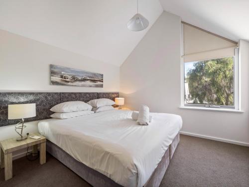 - une chambre avec un grand lit blanc et une fenêtre dans l'établissement 63@CapeView, Geographe bay, à Busselton