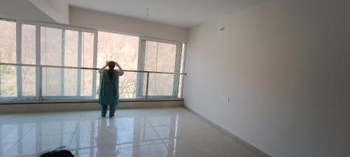 Una mujer parada en una habitación mirando por una ventana en Indilife nature, en Pune