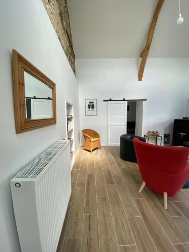 un salon avec une chaise rouge et un canapé dans l'établissement La Mauvernière, 2 gîtes indépendants, 1 grande piscine extérieure, jardin arboré, à Descartes