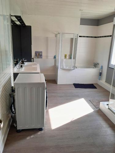 La grande salle de bains est pourvue de 2 lavabos et d'une baignoire. dans l'établissement Villa 4 Ch Plein Centre Havre, au Havre