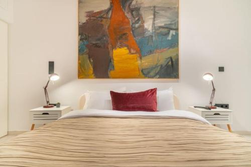 a bedroom with a bed with a painting on the wall at The HostMaster Gazi La Grande Maison in Athens