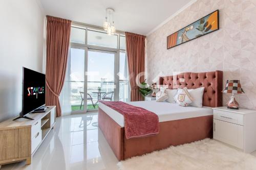 a bedroom with a bed and a tv and a balcony at Staycae Holiday Homes - Carson Towers in Dubai