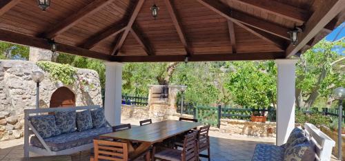 a wooden pavilion with a table and a couch on a patio at Trullo Grande Noce in Ostuni