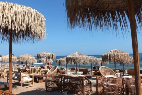 ヘルソニソスにあるOV Suites "by Checkin"のビーチ(テーブル、椅子、わらパラソル付)
