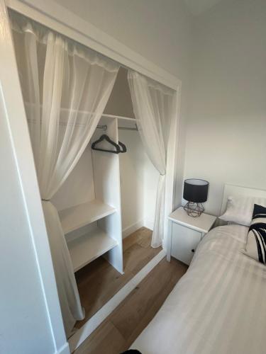 a white bedroom with a bed and a shelf at Class Apartments in Peterhead
