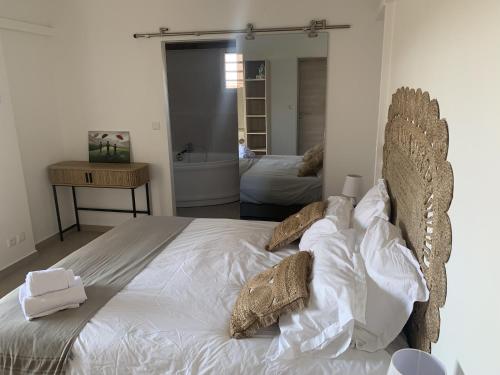 a bedroom with a bed with white sheets and pillows at Nakolodge - 2 chambres -piscine et jardin privatifs in Sainte-Anne
