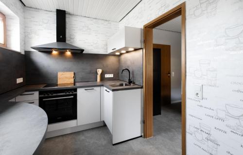uma cozinha com armários brancos, um lavatório e um fogão em Wäller Abendsonne em Westerburg