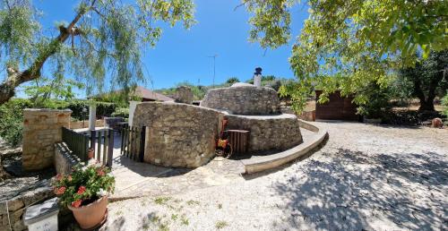 une cour avec un bâtiment en pierre et une clôture dans l'établissement Trullo Grande Noce, à Cisternino