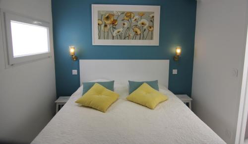 Un dormitorio con una cama blanca con almohadas amarillas. en Clos Emilie, en La Seyne-sur-Mer