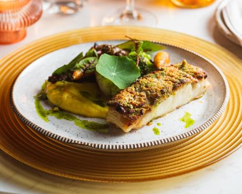 a plate of food with a piece of fish and vegetables at Naatooh Guest Houses in Florianópolis