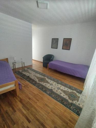 a bedroom with two beds and a rug at Villa Ema rooms in Niš