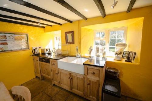 kuchnia z białym zlewem i żółtą ścianą w obiekcie Bridge Cottage Withypool w mieście Withypool