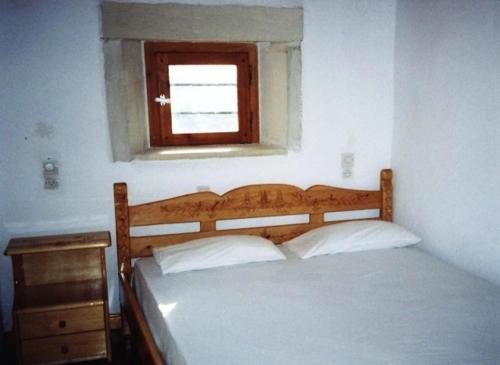 a bedroom with a bed with a window and a wooden headboard at Patsianos Traditional House in Frangokastello