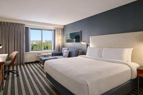 um quarto de hotel com uma cama grande e uma cadeira em Courtyard by Marriott Los Angeles Westside em Los Angeles