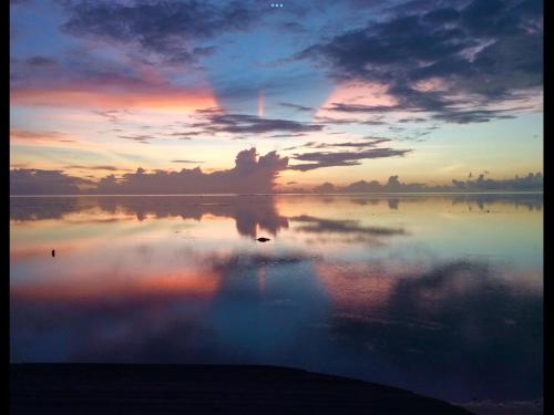 a reflection of a sunset in a body of water at Faré Paloma Moorea in Moorea