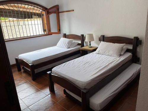 - 2 lits jumeaux dans une chambre avec fenêtre dans l'établissement Casa 30 m da praia,condomínio Tenório, à Ubatuba