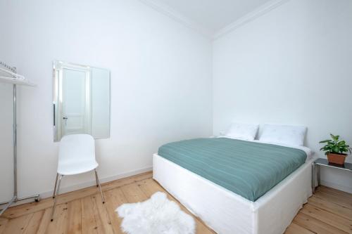 a white bedroom with a bed and a chair at HB apartments Tabukashvili in Tbilisi City