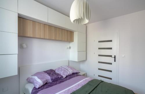 a bedroom with white cabinets and a purple bed at Apartament Sztutowo by Ski and Sea in Sztutowo