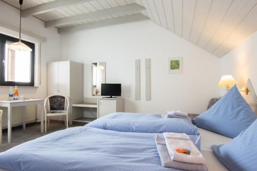 een slaapkamer met 2 blauwe bedden en een bureau bij Pension Krone in Schwäbisch Gmünd