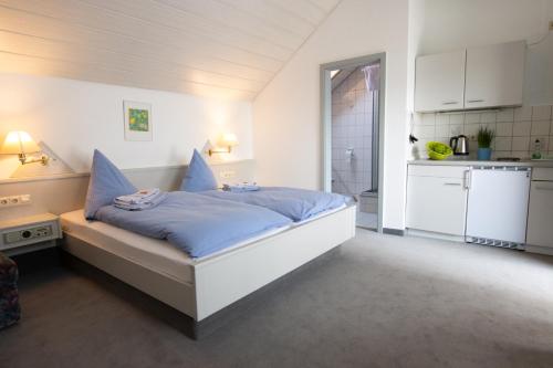 a bedroom with a bed with blue sheets and a kitchen at Pension Krone in Schwäbisch Gmünd