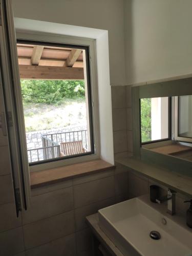 ein Bad mit einem Waschbecken und einem Fenster in der Unterkunft Sobe Lavanda in Kojsko