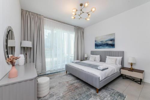ein weißes Schlafzimmer mit einem Bett und einem großen Fenster in der Unterkunft Luxury apartments at La Vie in Dubai