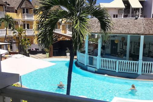 a palm tree in the swimming pool at a resort at Appart Blue Beach piscine et lagon à l'Ermitage in Saint-Paul