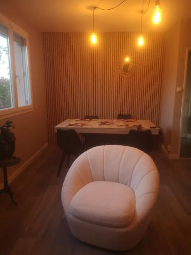 une chaise blanche dans une chambre avec une table dans l'établissement Le pastel, à Albi