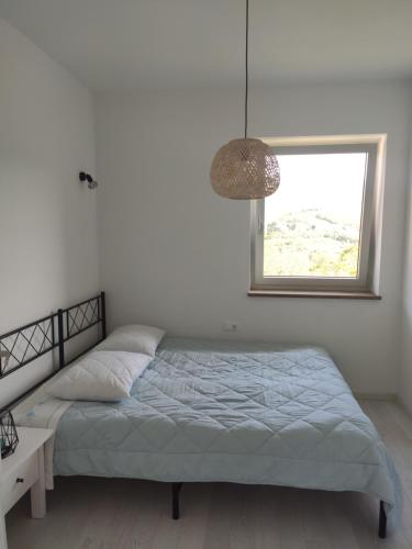 a white bedroom with a bed and a window at Sobe Lavanda in Kojsko