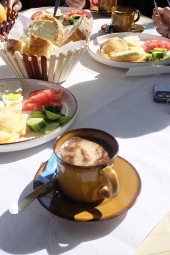 a table with plates of food and a cup of coffee at ROLEO Guest House in Lin