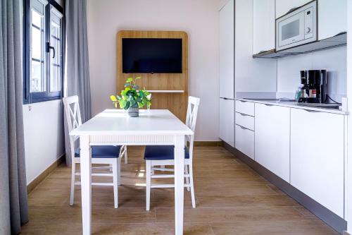 a white kitchen with a white table and chairs at Hotel Cordial Marina Blanca in Playa Blanca