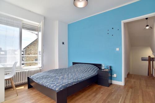 une chambre avec un lit et un mur bleu dans l'établissement Douceur Malouine - Maison familiale avec jardin, à Saint-Malo