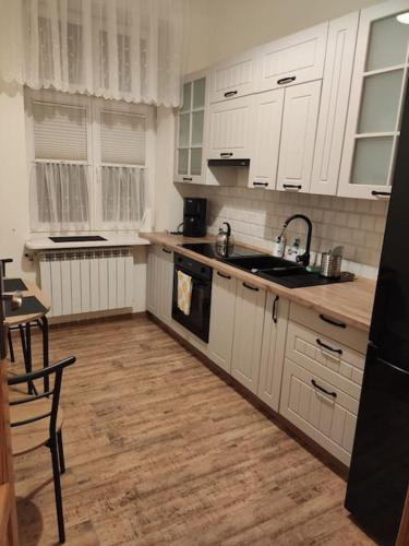 kuchnia z białymi szafkami i drewnianą podłogą w obiekcie Kamienica Mikołajki w mieście Mikołajki
