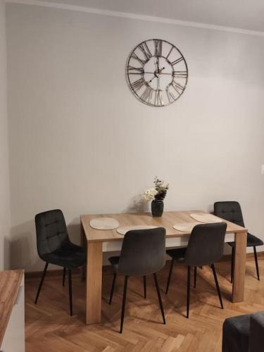 stół jadalny z krzesłami i zegarem na ścianie w obiekcie Kamienica Mikołajki w mieście Mikołajki