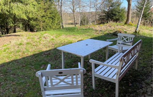 a picnic table and two benches in a field at Amazing Home In Knäred in Knäred