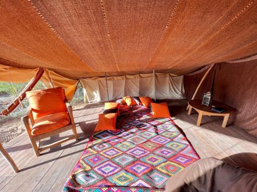 a bed and a chair in a tent at Le Khaïma Bio, Oasis écologique au bord de l'océan in Douaïra