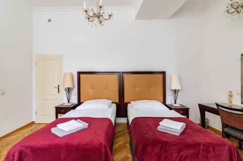 a bedroom with two beds with red covers and a chandelier at Studio an der Therme in Baden-Baden