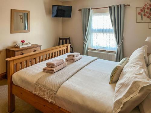 a bedroom with a large bed with towels on it at Elens Place in Tywyn
