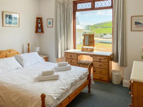 a bedroom with a bed and a dresser and a window at Marine Mews 3 in Salcombe