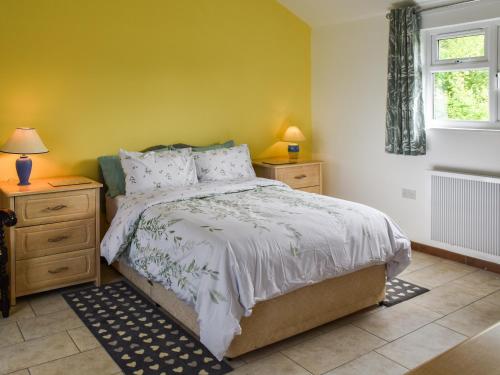um quarto com uma cama e duas mesas de cabeceira e uma janela em Stable Cottage - Uk45134 em Barnby